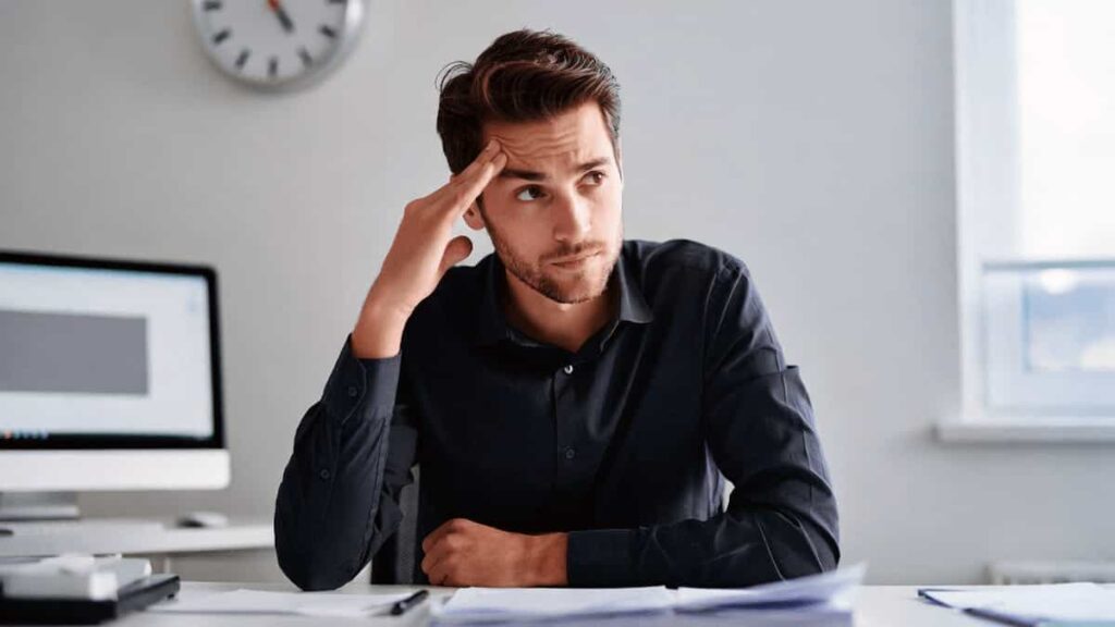 A thoughtful professional man sitting at a desk, representing analytical thinking and strategic decision-making protocols.