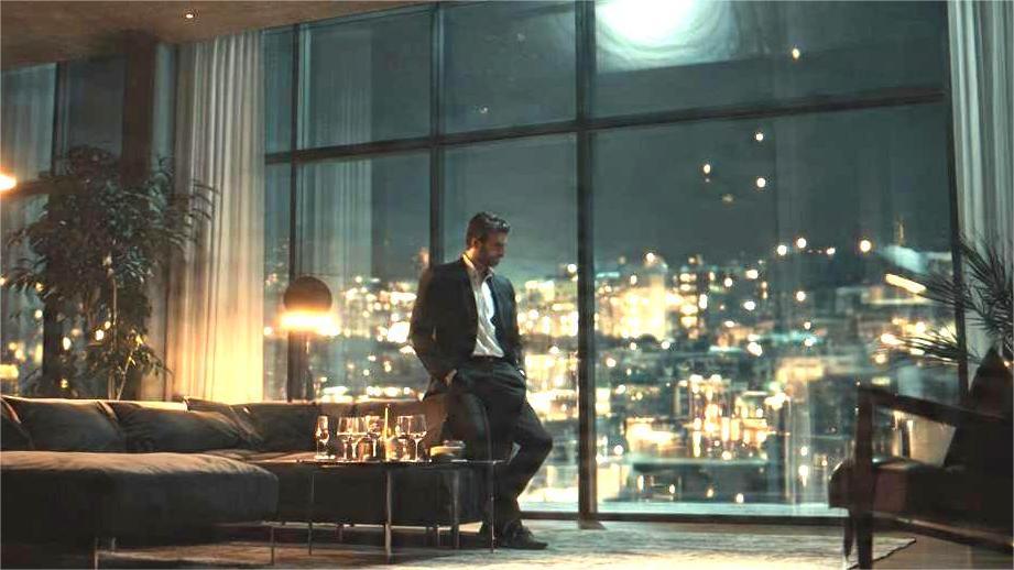 A photograph in a frame with text. The image shows a man in a suit standing by a large window in a luxury apartment at night, looking out at the city. The text "THE VOID: WHY PEOPLE NEED PURPOSE TO FEEL FULFILLED" is in the picture. A smaller plaque below reads: "Capturing a moment of profound isolation and lack of purpose despite material comfort."