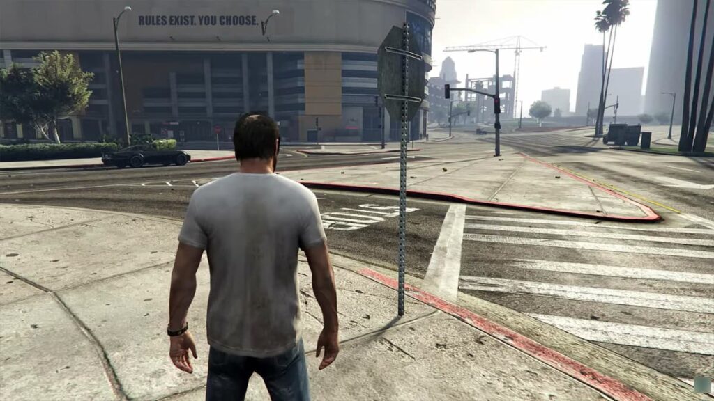 A player character stands next to a parked car on a sunny city street, looking at a red traffic light.