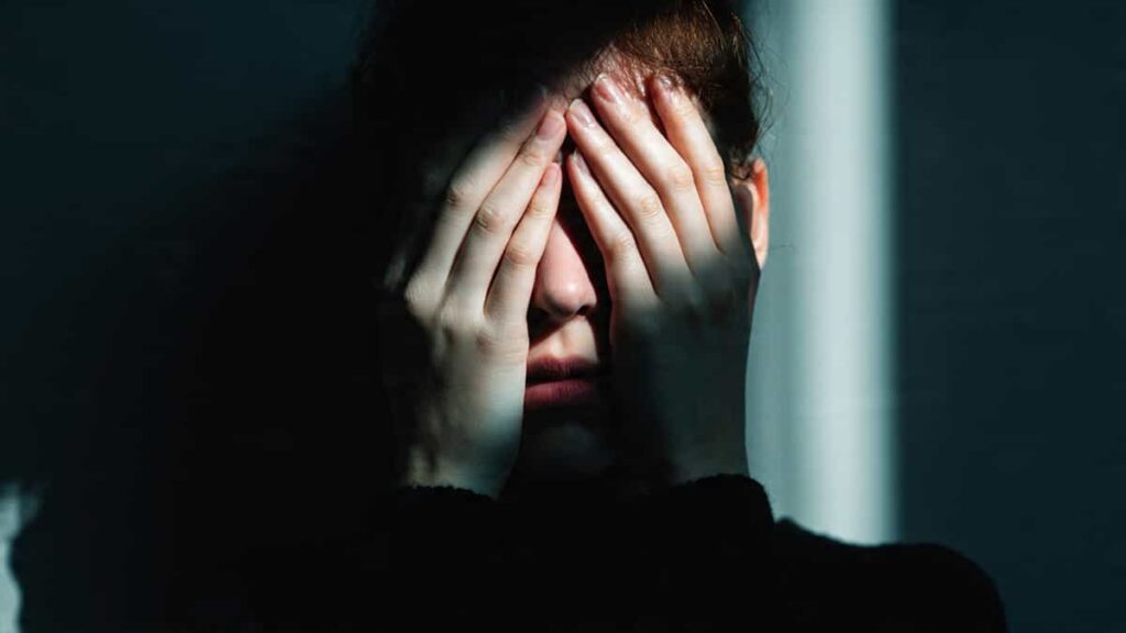 Person covering eyes symbolizing denial and ignoring reality in the innocent archetype shadow side