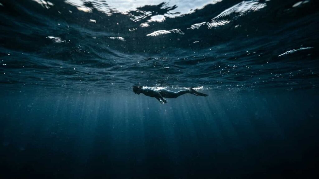 Person floating above deep dark ocean water creating a feeling of anxiety and fear