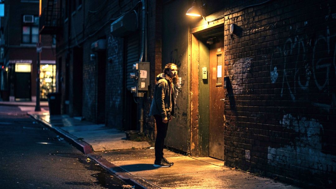 Person hesitating at a dim alley entrance, illustrating the brain's instantaneous assessment of environmental safety signals.