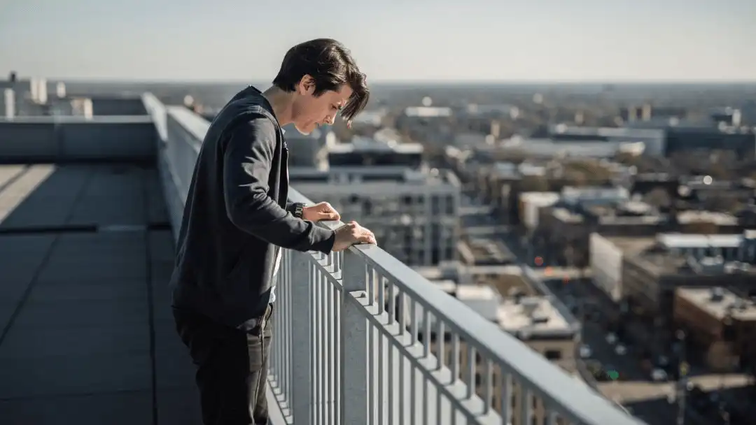 Person at the edge of a high rooftop, illustrating the brain's automatic fear response to the possibility of falling.